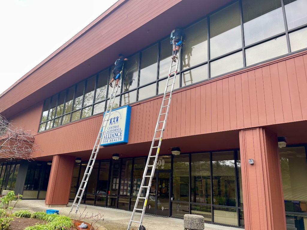 Commercial window cleaning crew on ladders at an office building