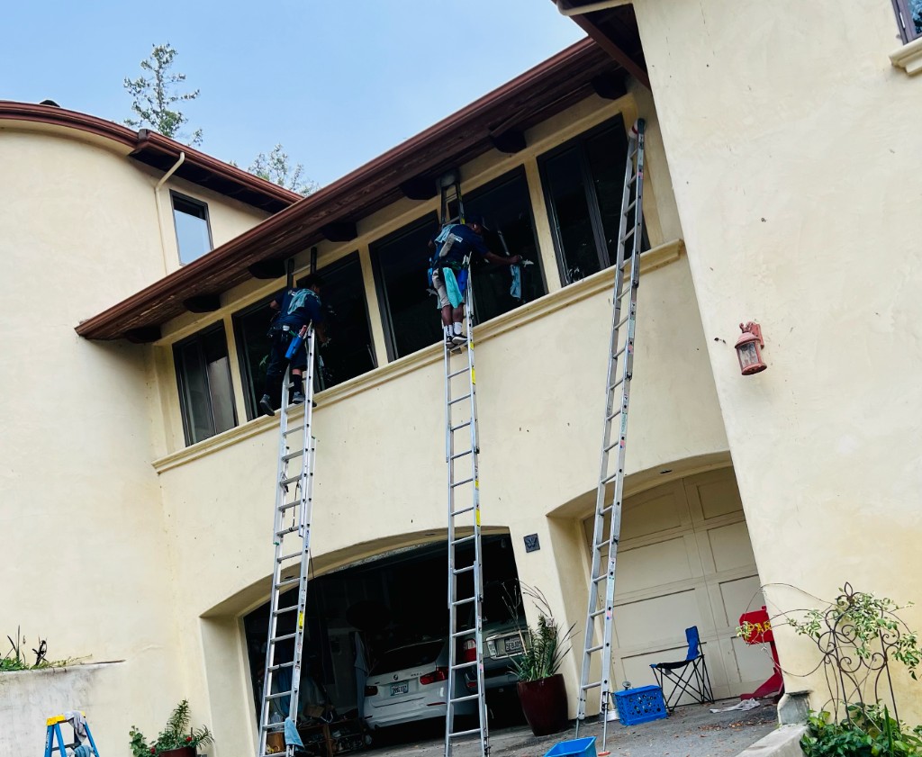 Window cleaning crew on ladders at a Santa Cruz home