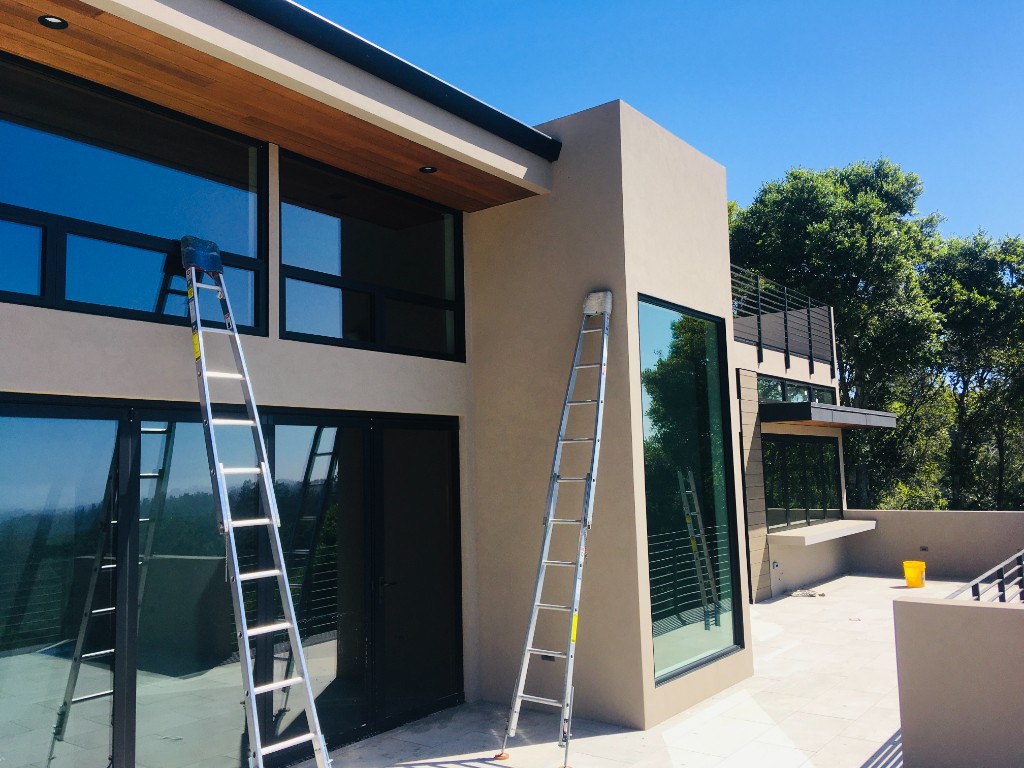 Ladder setup for window cleaning on a modern hilltop home
