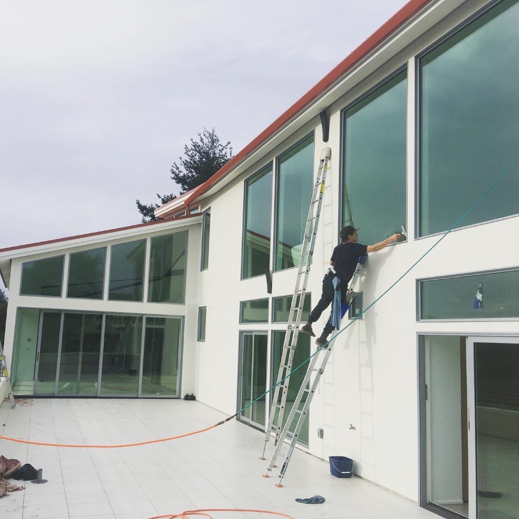 Window Cleaner on Ladder at Modern Home